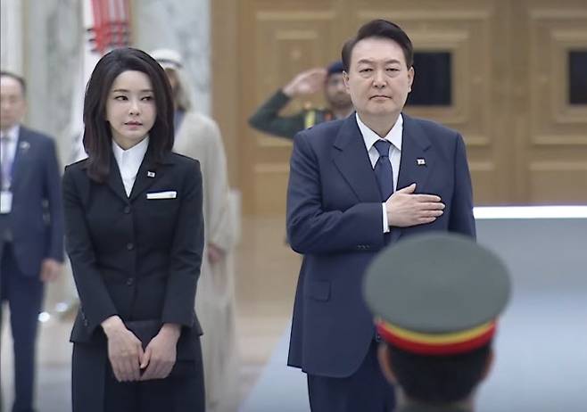 UAE 국가 도중 의례하고 있는 윤 대통령, 김건희 여사와 뒤편에 도열한 추경호 경제부총리는 의례를 하지 않고 있다. UAE는 국가나 국기에 대해 가슴에 손을 얹는 의례(chest salute)를 하지 않는 나라다. 에미리트통신 유튜브 영상 캡처.