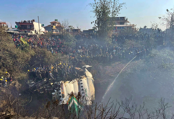 네팔 구조대원들과 민간인들이 지난 15일(현지시간) 네팔 포카라 추락 여객기 잔해 주위에 모여있다. [사진=뉴시스]
