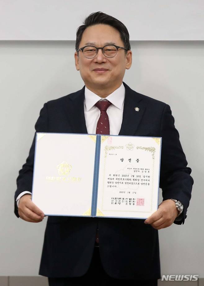 [서울=뉴시스] 김선웅 기자 =  제52대 대한변호사협회장으로 당선된 김영훈 변호사가 17일 서울 서초구 대한변협회관에서 열린 당선증 교부식에서 당선증을 받은 후 사진촬영을 하고 있다. 2023.01.17. mangusta@newsis.com