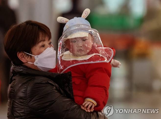 (EPA=연합뉴스) 지난 14일 중국 상하이 철도역에서 한 여성이 아이를 안고 걸어가는 모습. 2023.1.17.