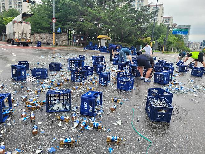 지난해 6월 29일 춘천시 퇴계동의 한 사거리에서 트럭에 실려있던 맥주병 2000여병이 바닥으로 떨어지는 사고가 발생, 길을 가던 시민들이 청소를 돕고 있다./뉴스1