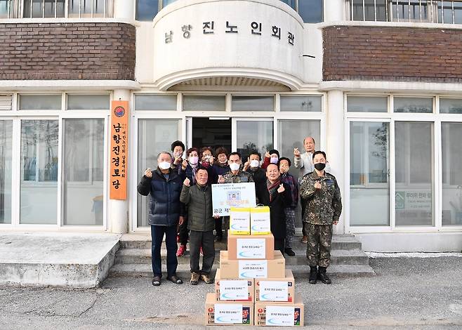 공군 제18전투비행단 오홍균 단장(가운데)이 부대 인근 남항진동 주민들에게 위문품을 전달하며 기념 촬영을 하고 있다.(공군 제공)