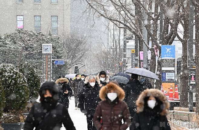 수도권 일대에 대설주의보가 발효된 26일 서울 종로구 광화문사거리 일대에 시민들이 내리는 눈을 맞으며 거리를 지나고 있다. 임세준 기자
