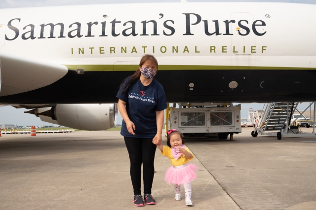 사마리안퍼스가 진행하는 '칠드런스하트 프로젝트'의 지원을 받은 아이가 엄마 손을 잡고 사마리안퍼스 비행기를 배경으로 사진을 찍고 있다. 사마리안퍼스코리아 제공