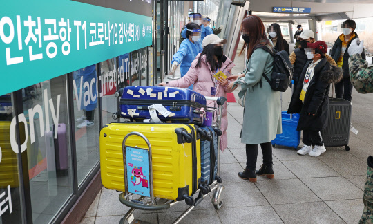 지난 8일 오후 인천국제공항 제1여객티미널을 통해 입국한 중국발 입국자들이 검역지원단의 안내를 받아 PCR 검사센터로 향하고 있다. [영종도=연합뉴스]