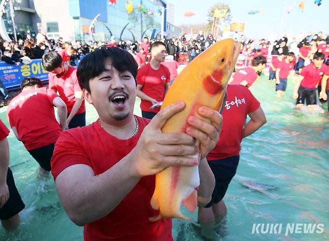 2023 평창송어축제 '황금 송어를 잡아라’ 이벤트에 참가한 방문객이 황금 송어를 잡고 환호성을 지르는 모습.