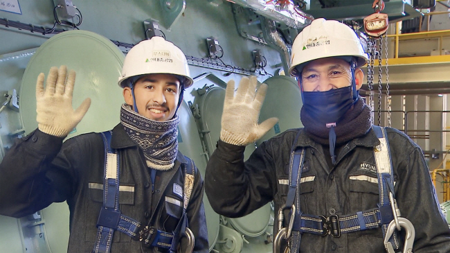 굴럼 무스타파 미르자이(왼쪽) 군과 그의 아버지 후세인 미르자이 씨 부자가 함께 근무하는 현대중공업 엔진기계사업부 안에서 손을 들어보이고 있다.  현대중공업 제공