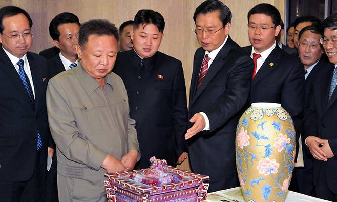 2011년 7월 당시 김정일 위원장(왼쪽)과 아들인 김정은 현 국무위원장(〃 두번째)이 평양을 방문한 중국 대표단한테 받은 도자기 등 선물을 감상하는 모습. 북한 선전매체 ‘조선의 출판물’ 캡처