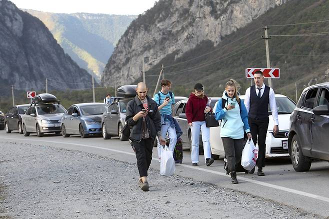지난 28일 러시아 사람들이 조지아 국경을 향해 걸어서 이동하고 있다. 국경 교차로에는 차량 행렬이 길게 늘어서 있다. 블라디미르 푸틴 대통령이 우크라이나 주둔 부대를 지원하기 위해 부분 동원을 지시한 지 하루 만에 많은 러시아인이 집을 떠나고 있다. AP=연합뉴스