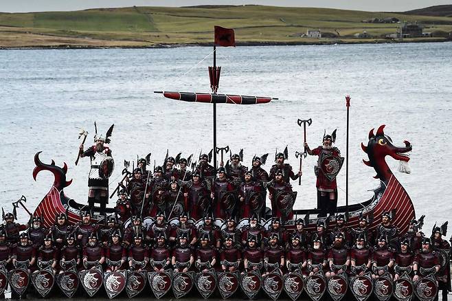 31일(현지시각) 영국 스코틀랜드 북동부의 셰틀랜드 러윅에서 바이킹 복장의 ‘업 헬리 아’ 참가자들이 갤리선과 함께 기념사진을 찍고 있다. 러윅/AFP 연합뉴스