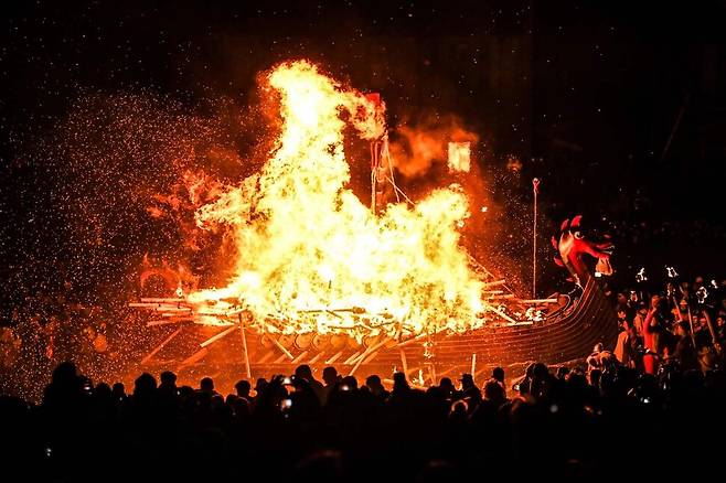 유럽 최대 규모의 불 축제 ‘업 헬리 아’가 31일(현지시각) 영국 스코틀랜드 북동부의 셰틀랜드 러윅에서 열려 행진을 마친 참가자들이 갤리선에 불을 붙이고 있다. 러윅/AFP 연합뉴스