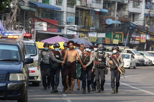 군부가 쿠데타를 일으킨 직후인 지난 2021년 2월26일 미얀마 최대도시 양곤에서 소총 등으로 무장한 경찰이 시위대로 보이는 남성을 붙잡아 어디론가 끌고 가고 있다. 양곤/AFP 연합뉴스