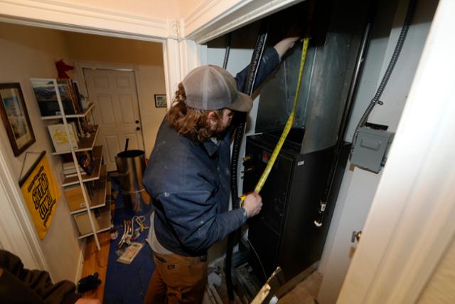 지난달 23일 미국 콜로라도주 덴버의 80년 된 가정집에서 주민이 히트펌프 설치를 위해 보일러실 크기를 측정하고 있다. AP연합뉴스