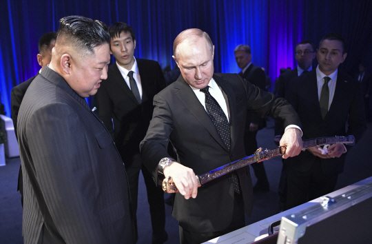 블라디미르 푸틴(오른쪽) 러시아 대통령이 2019년 4월 25일(현지시간) 블라디보스토크 극동연방대학에서 확대 정상 회담 후 열린 연회에서 김정은(왼쪽) 북한 국무위원장에게 줄 선물을 설명하고 있다. AP 뉴시스