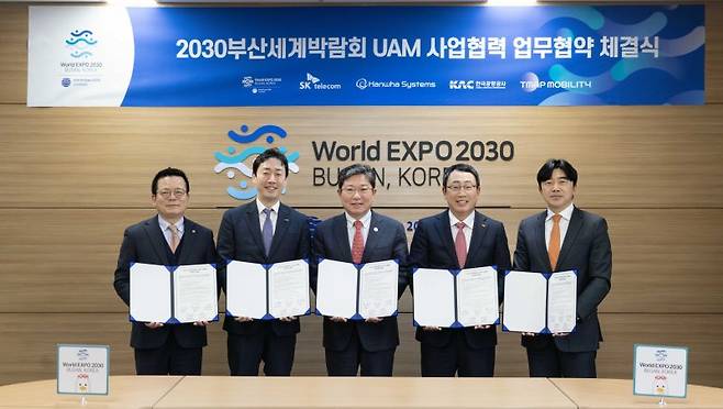 SK텔레콤, 한화시스템, 한국공항공사, 티맵모빌리티는 부산세계박람회 유치위원회와 부산엑스포 유치를 위한 도심항공교통(UAM) 사업 협력 업무협약(MoU)을 6일 체결했다. 어성철 한화시스템 사장, 윤형중 한국공항공사 사장, 윤상직 부산세계박람회 유치위원장, SKT 유영상 사장, 이종호 티맵모빌리티 사장(왼쪽 첫번째부터)이 협약식을 마치고 기념 촬영을 하고 있다. SKT 제공