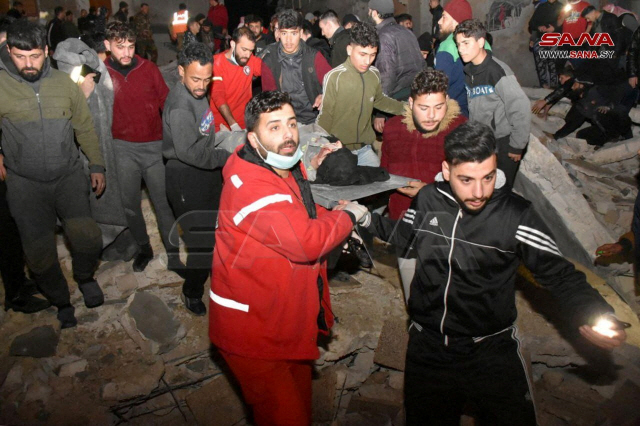 ▲ 지진 여파가 미친 시리아 중부 도시 하마의 무너진 건물에서 부상자를 이송하는 구조대원들.