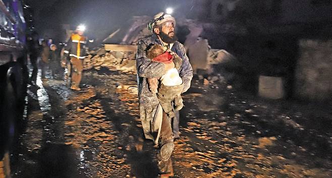 "제발 이 아이만은…" - 6일(현지 시각) 규모 7.8의 강진이 발생한 시리아 북서부 이들리브주 자르다나에서 한 구조대원이 건물 잔해에서 구조한 아이를 품에 안고 의료진을 찾아 달려가고 있다. 주민들이 대부분 잠든 새벽에 지진이 발생했고, 무너진 건물 잔해에 깔린 사람이 많을 것으로 보여 희생자 숫자는 더 늘어날 전망이다.  /AFP 연합뉴스