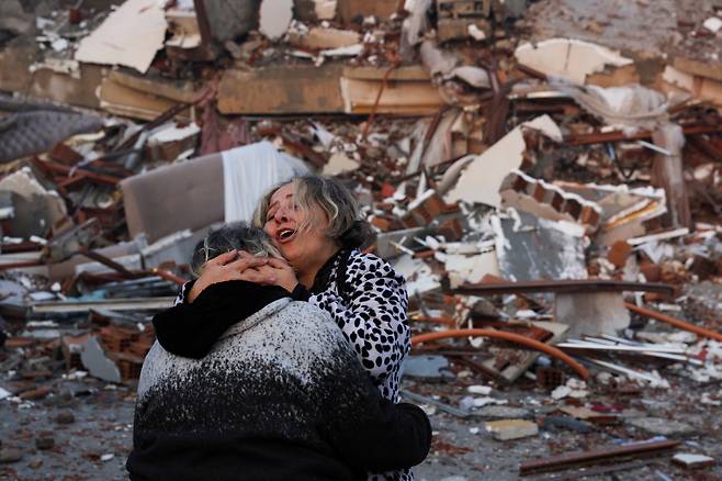 강진 발생 다음날인 7일(현지시간) 지진으로 붕괴한 튀르키예 하타이의 건물 잔해 앞에서 두 사람이 서로 끌어안고 있다. [연합]
