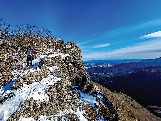 쌀바위 인근의 암봉을 오르는 등산인너머로 울산의 산들과 동해가 펼쳐진다.