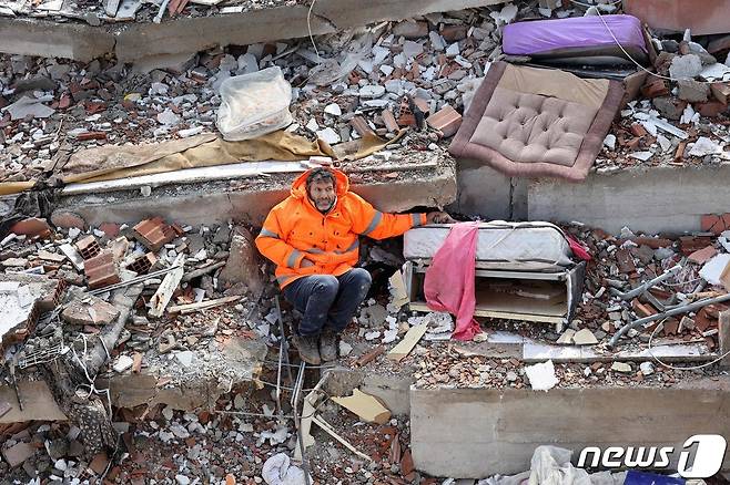 튀르키예 카라만마라슈의 건물 잔해에서 메수트 한제르라는 남성이 침대 위에서 죽은 딸의 손을 잡고 있다. ⓒ AFP=뉴스1