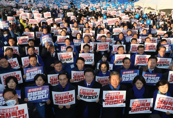 4일 서울 남대문과 시청역 사이 대로에서 열린 더불어민주당의 장외 집회. 이재명 당 대표가 의원들 사이에 앉아 ‘난방비 폭탄 못살겠다’고 적힌 손팻말을 들고 있다. [뉴스1]