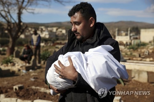 7일(현지시간) 시리아 북서부 알레포주 아프린시 진데리스 마을에서 한 주민이 지진으로 숨진 아기를 안고 묘지로 향하고 있다. [사진출처=연합뉴스]