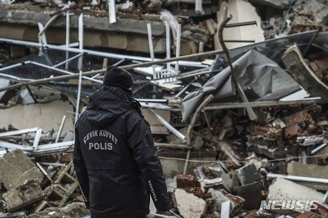 [가지안테프=AP/뉴시스] 6일(현지시간) 튀르키예 가지안테프에서 한 경찰관이 구조대와 함께 지진으로 파괴된 건물을 수색하고 있다.
