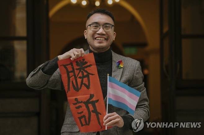 지난 6일(현지시간) 홍콩 트렌스젠더 활동가 헨리 에드워드 쯔가 홍콩 법원의 판결을 환영하며 ‘승소’라고 적힌 종이를 들고 있는 모습. 사진=연합뉴스