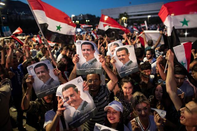 2021년 5월 바샤르 알 아사드 시리아 대통령 지지자들이 시리아 수도 다마스쿠스에서 아사드 대통령의 4선 성공을 축하하며 그의 사진과 국기를 흔들고 있다. 이로써 2000년 정권을 잡은 아사드 대통령은 총 28년간 시리아를 철권통치하게 됐다. 다마스쿠스=AP 연합뉴스