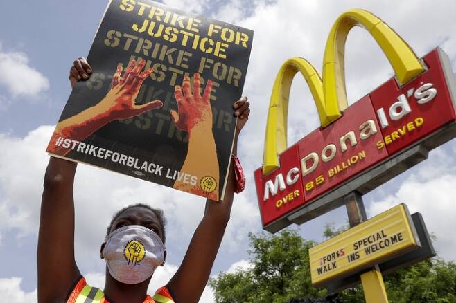미국 위스콘신주 밀워키의 한 맥도널드 매장 앞에서 인종차별 항의 시위와 연대한 동맹 파업에 참여한 한 노동자가 ‘정의를 위한 파업’이라고 쓰인 팻말을 들고 있다. 밀워키 | AP연합뉴스