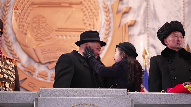 This image, captured from footage of North Korea’sstate-run Korean Central Television on Thursday shows North Korean leader Kim Jong-un’s secondborn daughter Ju-ae touching her father’s cheek while watching a nighttime military parade held the previous day to mark the 75th anniversary of the founding of the armed forces. (Yonhap)