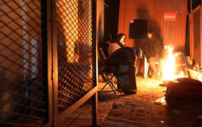 8일 오후(현지시간) 튀르키예 이스켄데룬 시내에서 시민들이 모닥불 앞에 앉아 추위를 녹이고 있다. <연합뉴스>