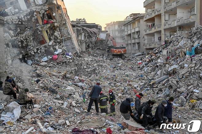 (하타이 AFP=뉴스1) 우동명 기자 = 14일 (현지시간) 규모 7.8의 지진이 강타한 튀르키예 하타이에서 폭격을 맞은 듯한 붕괴된 건물의 잔해 주변서 주민들이 시신 백을 옮기고 있다. ⓒ AFP=뉴스1 Copyright (C) 뉴스1. All rights reserved. 무단 전재 및 재배포 금지.