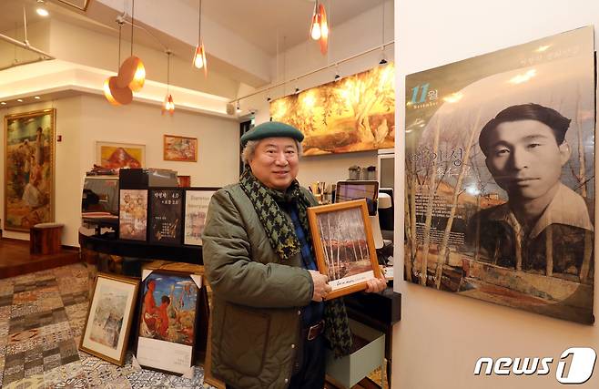 '천재화가 이인성(1912~1950)'의 아들 이채원 이인성기념사업회 회장이 아버지 사진 옆에서 포즈를 취했다. 손에 든 그림은 이인성의 '겨울 어느날'. 이인성이 신촌 이화여대 강사 시절 북아현 굴레방다리 인근 풍경 그린 것이라고 했다.