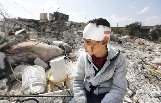 지진으로 부모를 잃은 한 시리아 소년이 알레포주 진데이리스 마을에서 잔해 더미 위에 앉아있다. AFP=연합뉴스