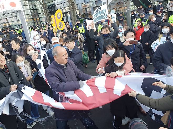 욱일기를 찢는 집회 참가자 (서울=연합뉴스) 김성민 수습기자 = 1일 오후 4시께 한일역사정의평화행동의 '104주년 3.1절 범국민대회'에 참가한 시민이 옛 일본 대사관 앞에서 욱일기를 찢고 있다. 2023.3.1 ksm7976@yna.co.kr