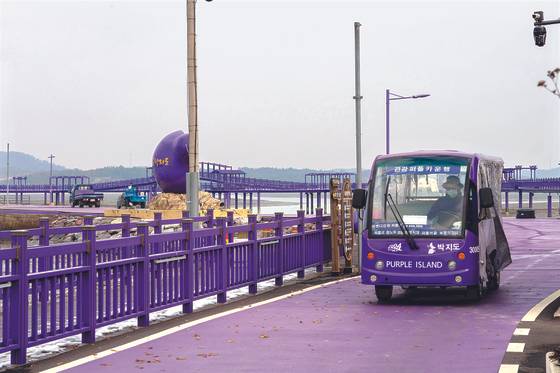 Purple Island's purple sightseeing cart is being driven on top of a purple road, surrounded by purple fences. [BAEK JONG-HYUN]