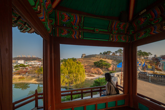 A woman sits inside Banghwasuryujeong Pavilion and observes the surrounding area. [GYEONGGI TOURISM ORGANIZATION]