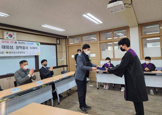 '키다리 경찰관'으로 알려진 윤흥용 대구 성서경찰서 교통사고 조사팀 경위가 1월 6일 모교인 성서초등학교 졸업식에 내빈으로 참석, 자신의 이름으로 장학금을 전달하고 있다. 대구 성서초등학교 제공.