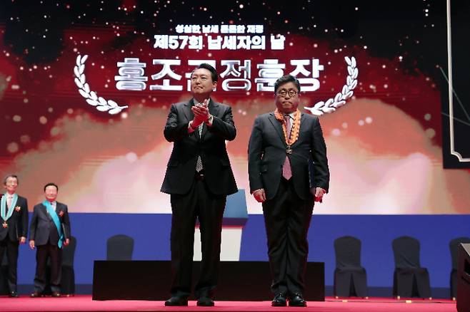 윤석열 대통령이 3일 서울 강남구 코엑스에서 열린 제57회 납세자의 날 기념식에서 서울시립대 박훈 교수에게 홍조근정훈장을 수여한 뒤 기념촬영하고 있다. 대통령실 제공