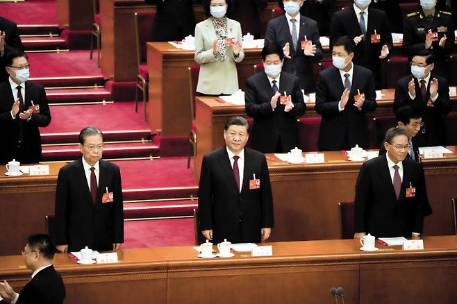 시진핑(가운데) 중국 국가주석이 10일(현지시간) 베이징 인민대회당에서 열린 전국인민대표대회(전인대) 전체회의에 도착해 참석자들로부터 박수를 받고 있다. 시 주석은 이날 다시 국가주석으로 선출돼 3연임을 공식 확정했다. 1949년 중화인민공화국(신중국) 건국 이후 최초의 국가주석 3연임이다. 시 주석 왼쪽과 오른쪽은 각각 자오러지·리창 중앙정치국 상무위원. [AP]