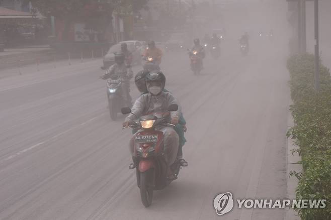 화산재 날리는 도로 (족자카르타 로이터=연합뉴스) 11일(현지시간) 인도네시아 중부 자바 족자카르타 인근 므라피 화산이 폭발하면서 화산재가 날리는 도로를 오토바이가 달리고 있다. 2023.3.11 photo@yna.co.kr