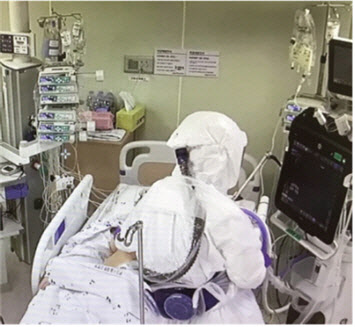 의료진이 음압병동에 있는 환자에게 폐 초음파를 수행하고 있는 모습.