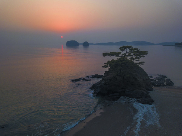 충남 서천군 비인면 선도리 당산바위 너머로 지는 해가 주위를 붉게 물들이고 있다. 멀리 바다 가운데 두 개의 섬이 쌍도다.