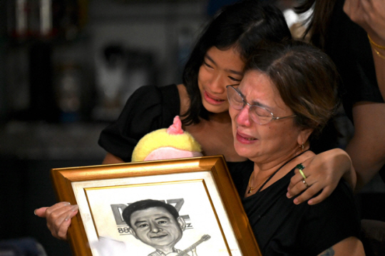 필리핀의 라디오 방송인 펄시벌 마바사의 가족들이 지난해 10월 4일 필리핀 마닐라의 자택에서 마바사의 캐리커처가 들어간 사진을 안고 눈물을 흘리고 있다. AFP 연합뉴스