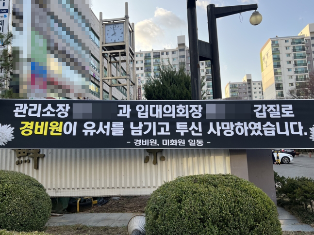 지난 14일 경비원 투신 사망사건이 일어난 서울 강남구의 한 아파트에 걸려 있던 추모 현수막. 연합뉴스