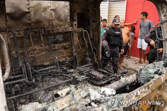 매일 밤 방화에 불안한 브라질 주민들 (나타우 AFP=연합뉴스) 16일(현지시간) 브라질 나타우에서 시민과 경찰이 방화 피해를 입은 화물차를 바라보고 있다. 2023.3.18