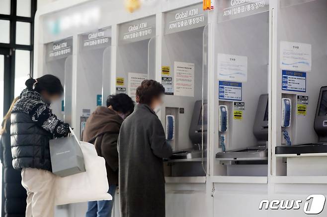 서울 시내 한 건물에 설치된 은행의 현금인출기(ATM)에서 시민들이 입출금을 하는 모습. 2022.12.27/뉴스1 ⓒ News1 황기선 기자