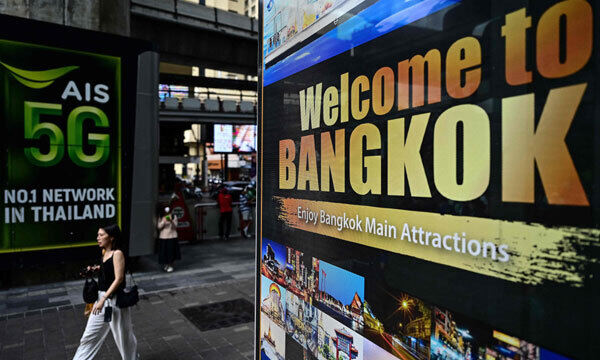 태국 시민이 17일 수도 방콕에서 관광명소 인근에 설치된 ‘방콕 방문을 환영한다’는 문구를 담은 입간판 옆을 걸어가고 있다. 방콕=AFP연합뉴스