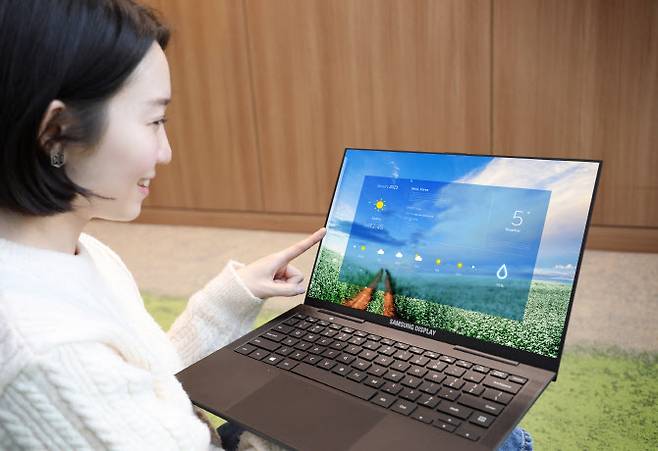 유기발광다이오드(OLED)가 적용된 노트북 콘셉트 제품을 손으로 작동시키고 있다. (사진=삼성디스플레이)